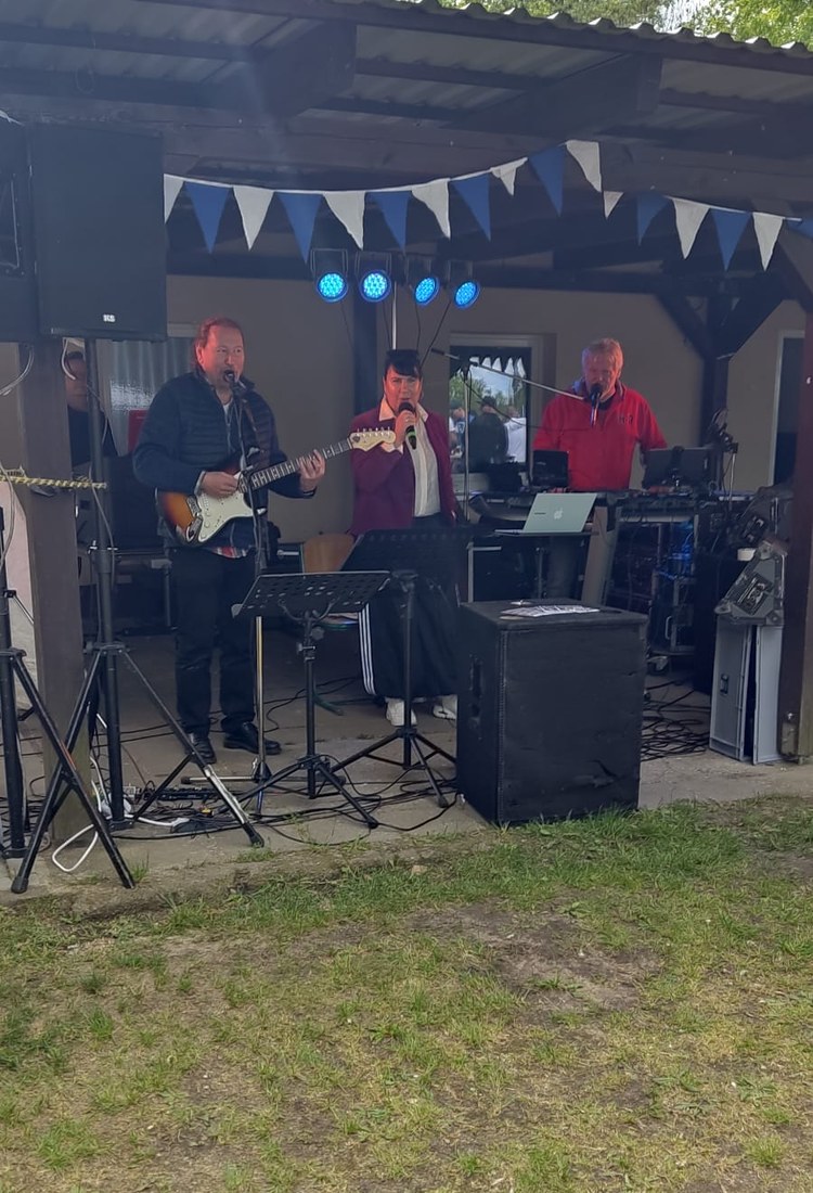 Michaela Zondler bei einem Live-Auftritt mit Band unter freiem Himmel, singend mit Mikrofon