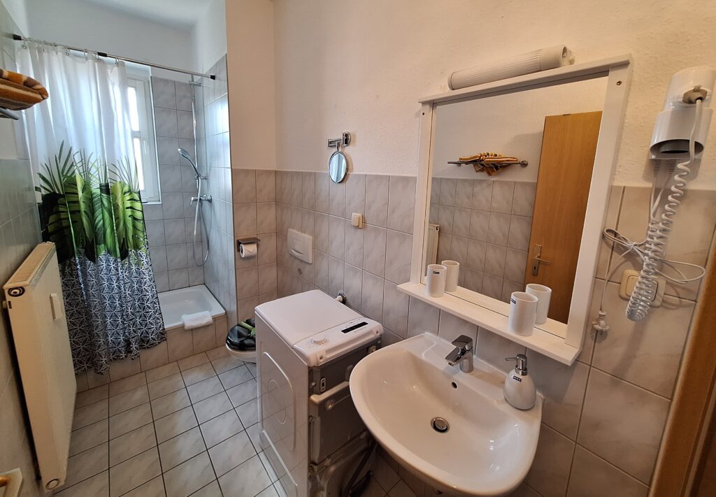 Badezimmer der MIWE Ferienwohnung mit Dusche, Waschmaschine und Waschtisch