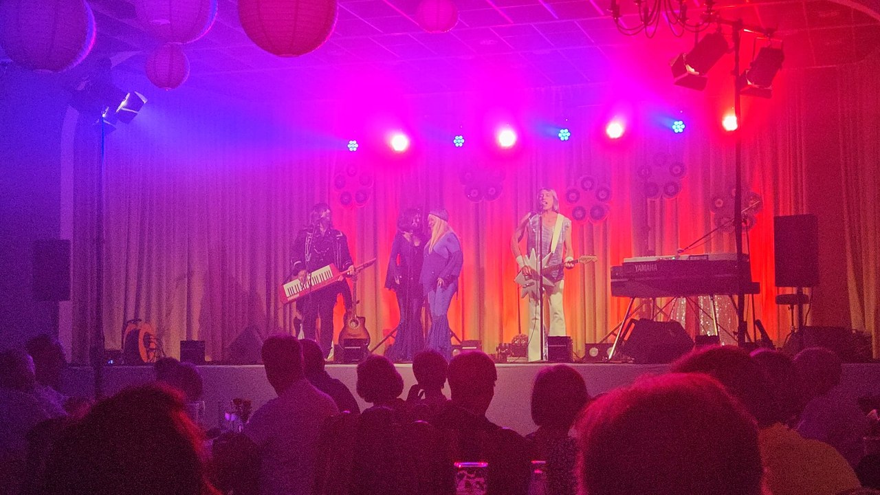 Die vier Musiker der ABBA Revival Show „A4u“ in Kostümen der 70er auf der Bühne des Gasthauses Sacro in blau-rotem Licht