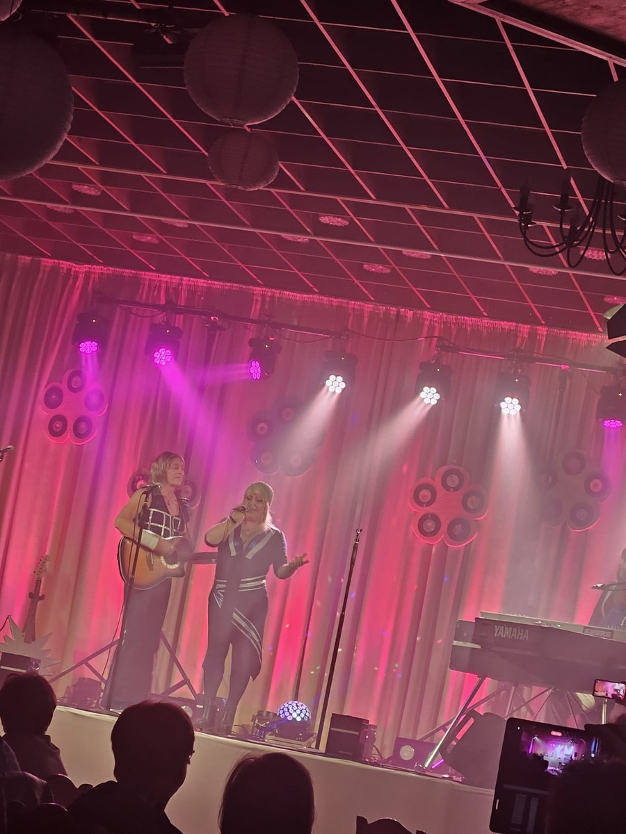 Zwei Sängerinnen der ABBA Revival Show „A4u“ beim gefühlvollen Duett im pinken Scheinwerferlicht des Gasthauses Sacro